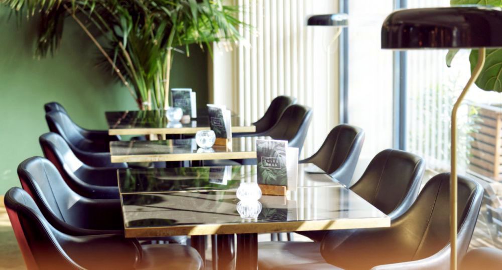 Volkshaus Leipzig Gastraum mit Tischen, Ledersesseln und Pflanzen im eleganten Ambiente